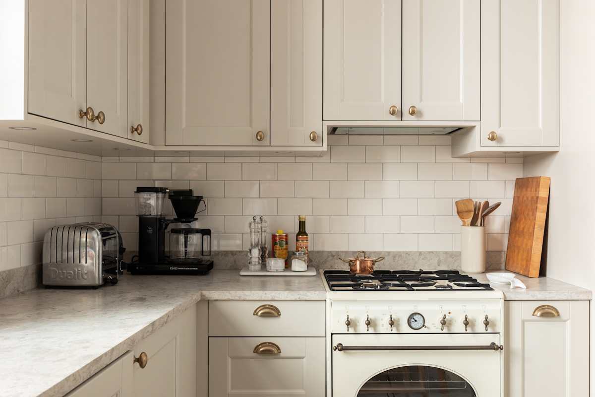 Sandra Beijers kök från Marbodal, Fagerö i den beige kulören Sand, med gasspis, vitt kakel som stänkskydd, och handtag i mässing.