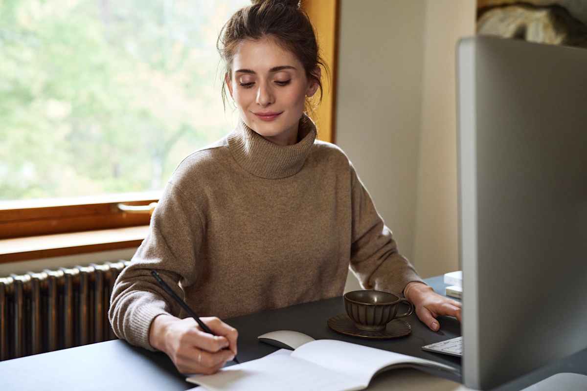 Kvinde gør anteckning framfør computeren
