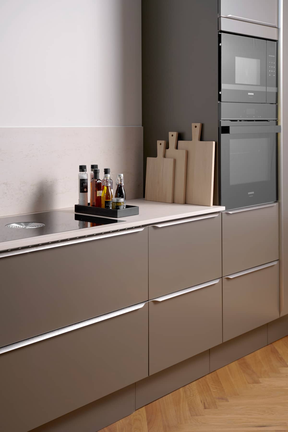 Minimalistisk brun køkken Newline Bark fra INVITA med indbygningsovne i højskabe, diskret greb i stål og lys beige bordplade med matchende splashback