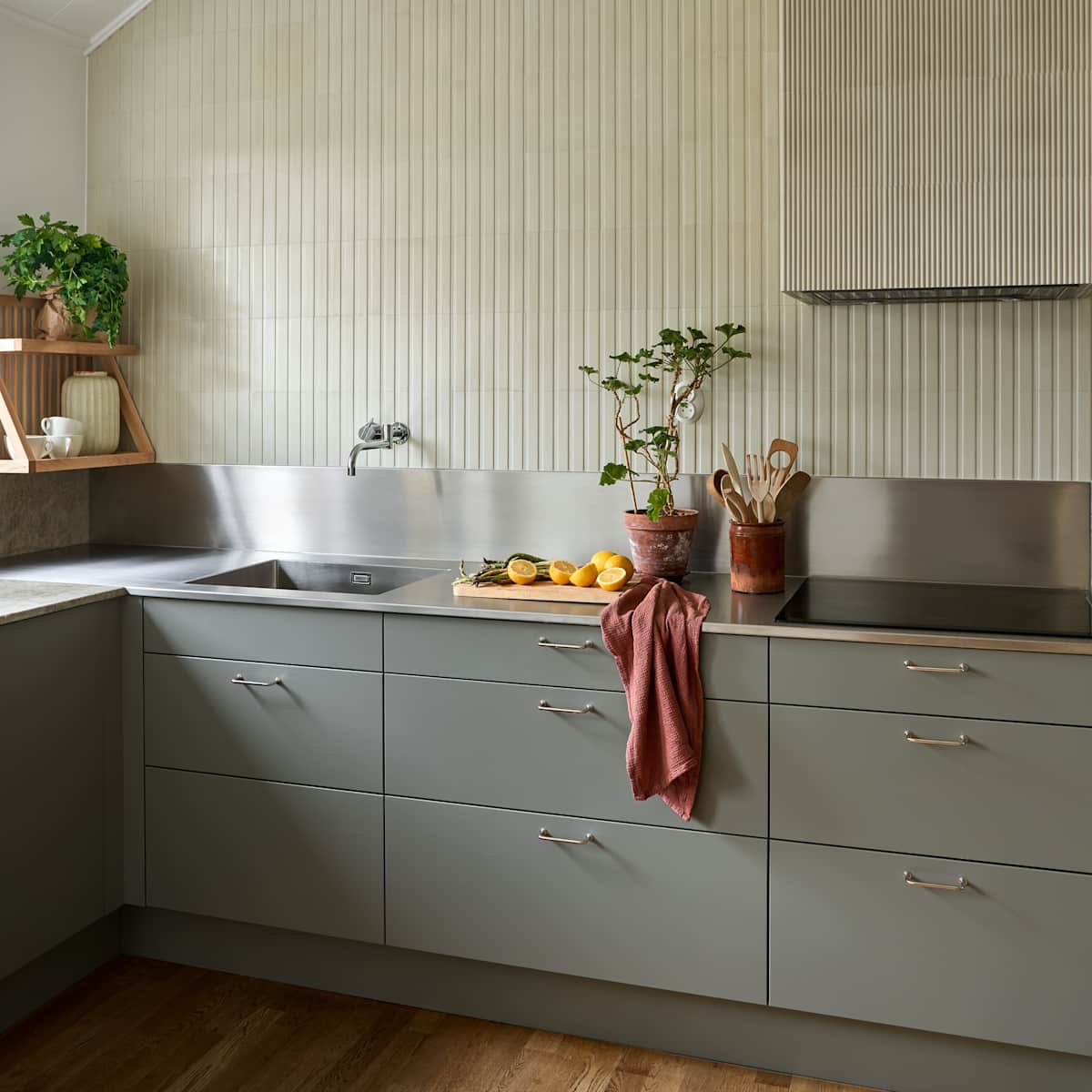 Lys grågrøn Athena Salvie køkken fra INVITA, håndtag och bordplade med splashback i rustfritt stål