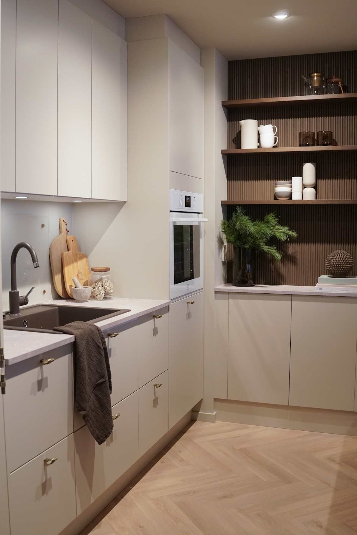Beige kjøkken med rifled tre veggpanel , sort vask og sort kran