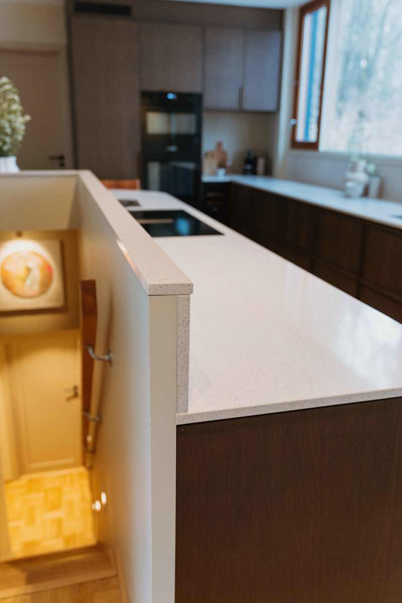 Eikekjøkkenet Favn fra Sigdal i beisfargen Nøtt, matchende tre håndtag, med benkeplate Blanco City fra Silestone og sort vask og sort blandebatteri.