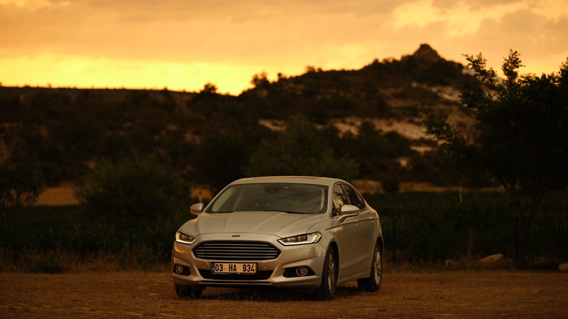 A car parked on a hillside at sunset