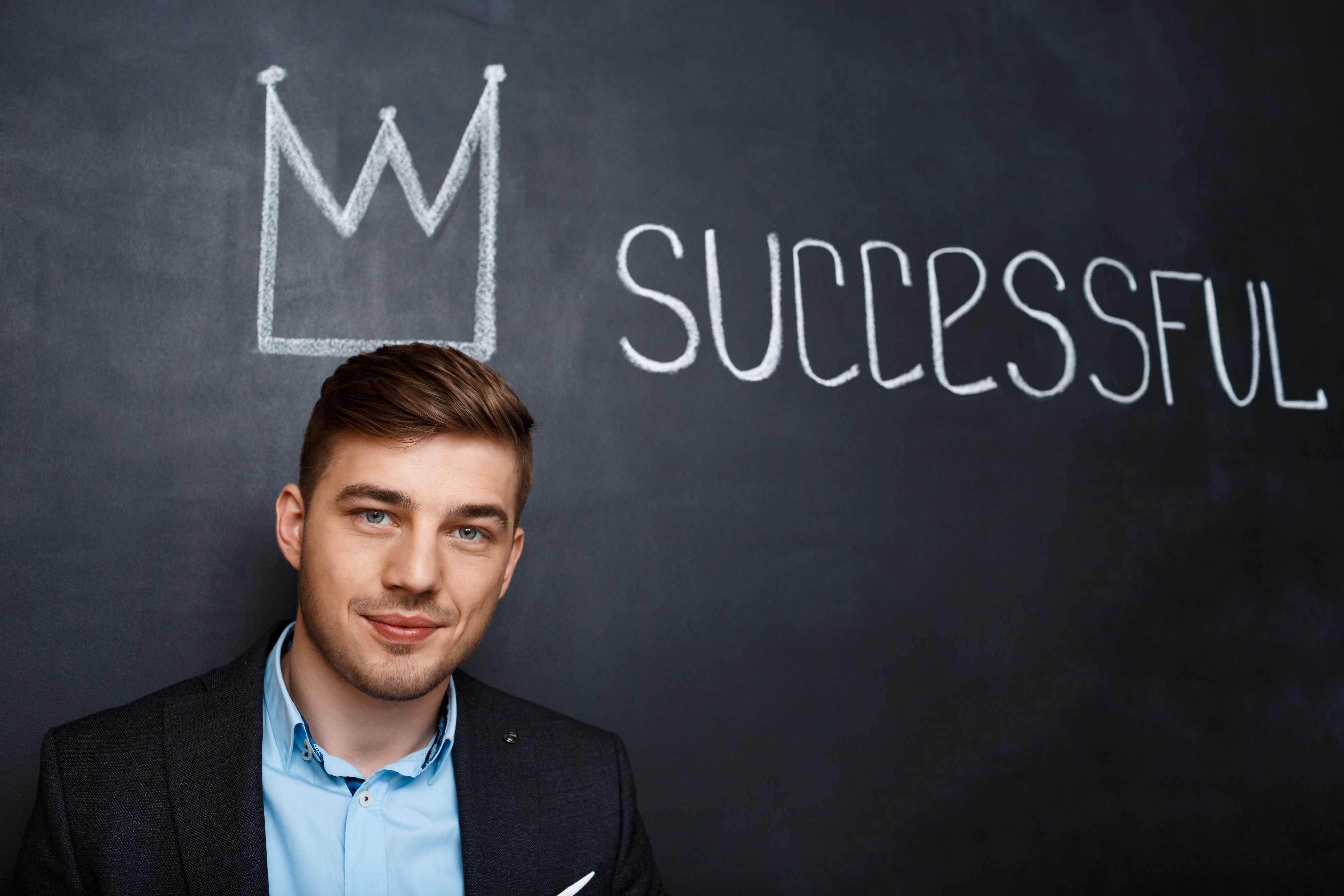 Man crown on head with blackboard written successful