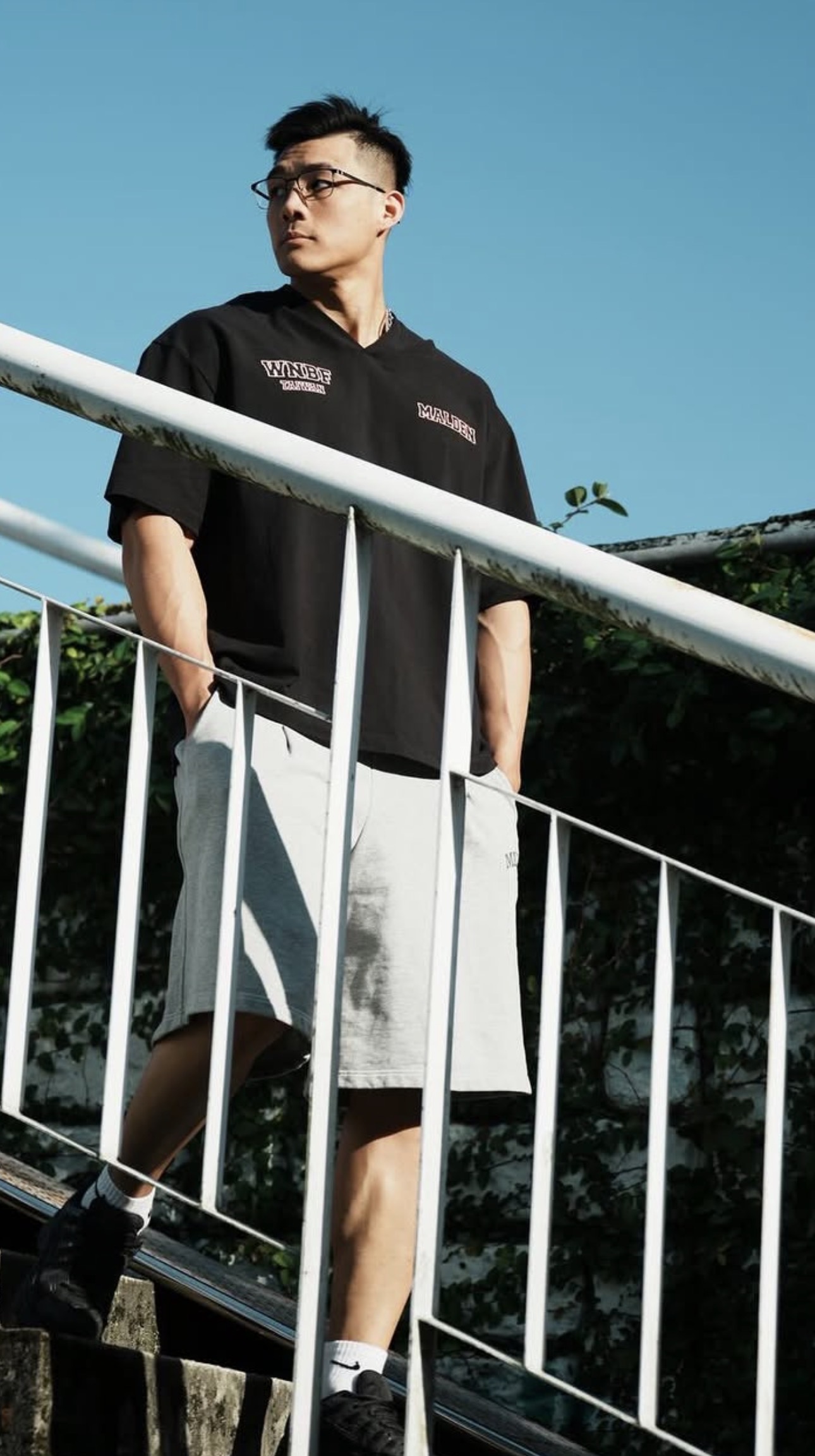 Fitness coach leaning on a railing in a red training top outdoors