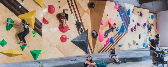 climbing gym interior with people bouldering on walls — Grotto Climbing & Yoga, from its own website