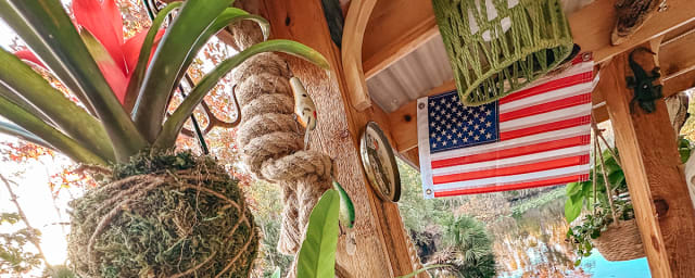 Wooden pergola with hanging plants, American flag, water view, tropical foliage — Wekiva Wild River Tours, from its own website