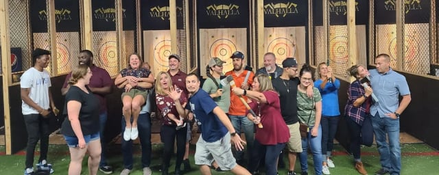Group of adults posing together indoors in front of axe-throwing target lanes — Valhalla Indoor Axe Throwing, from its own website