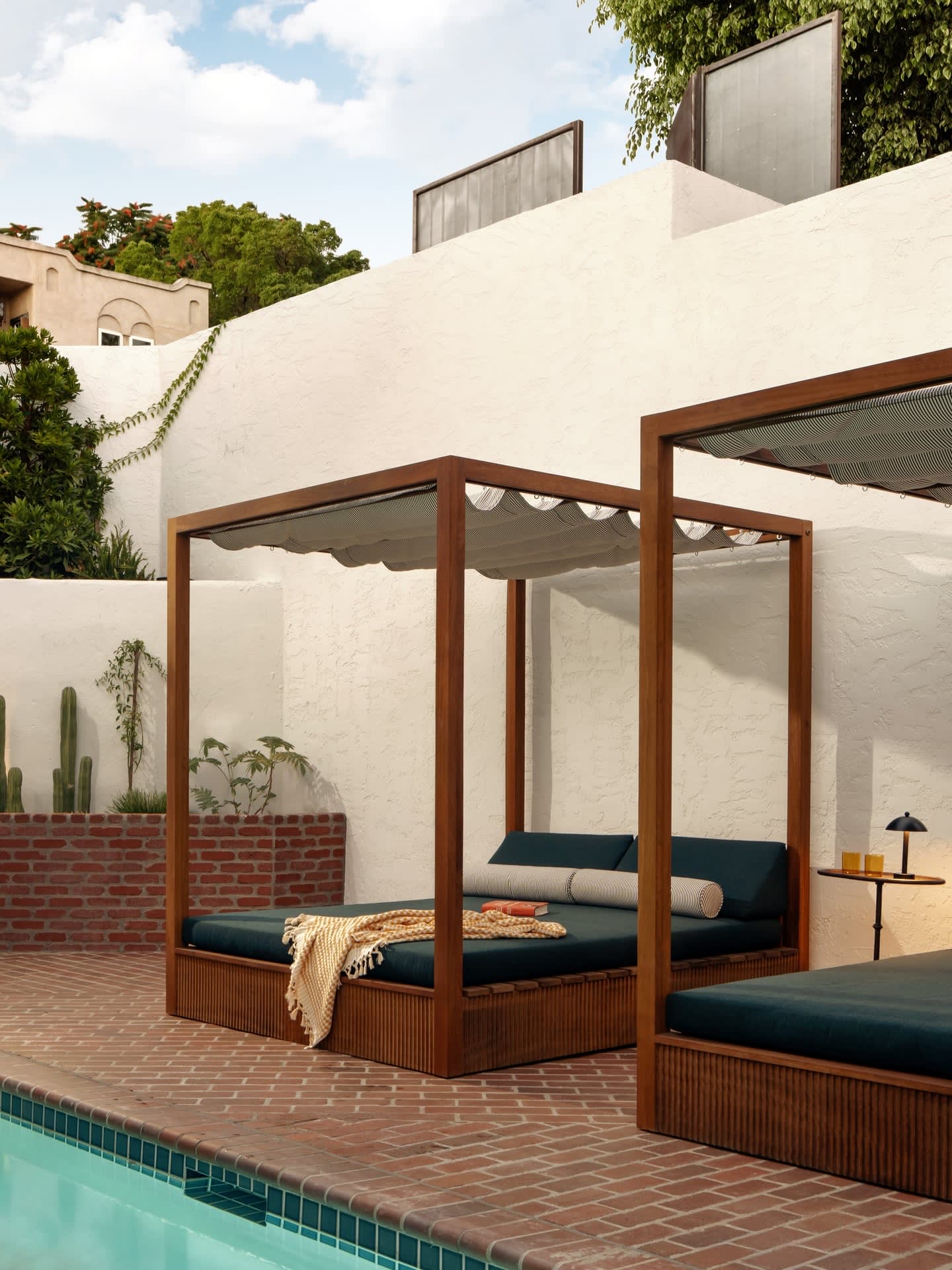 Daybeds under a wooden pergola beside the Hotel Lucile pool
