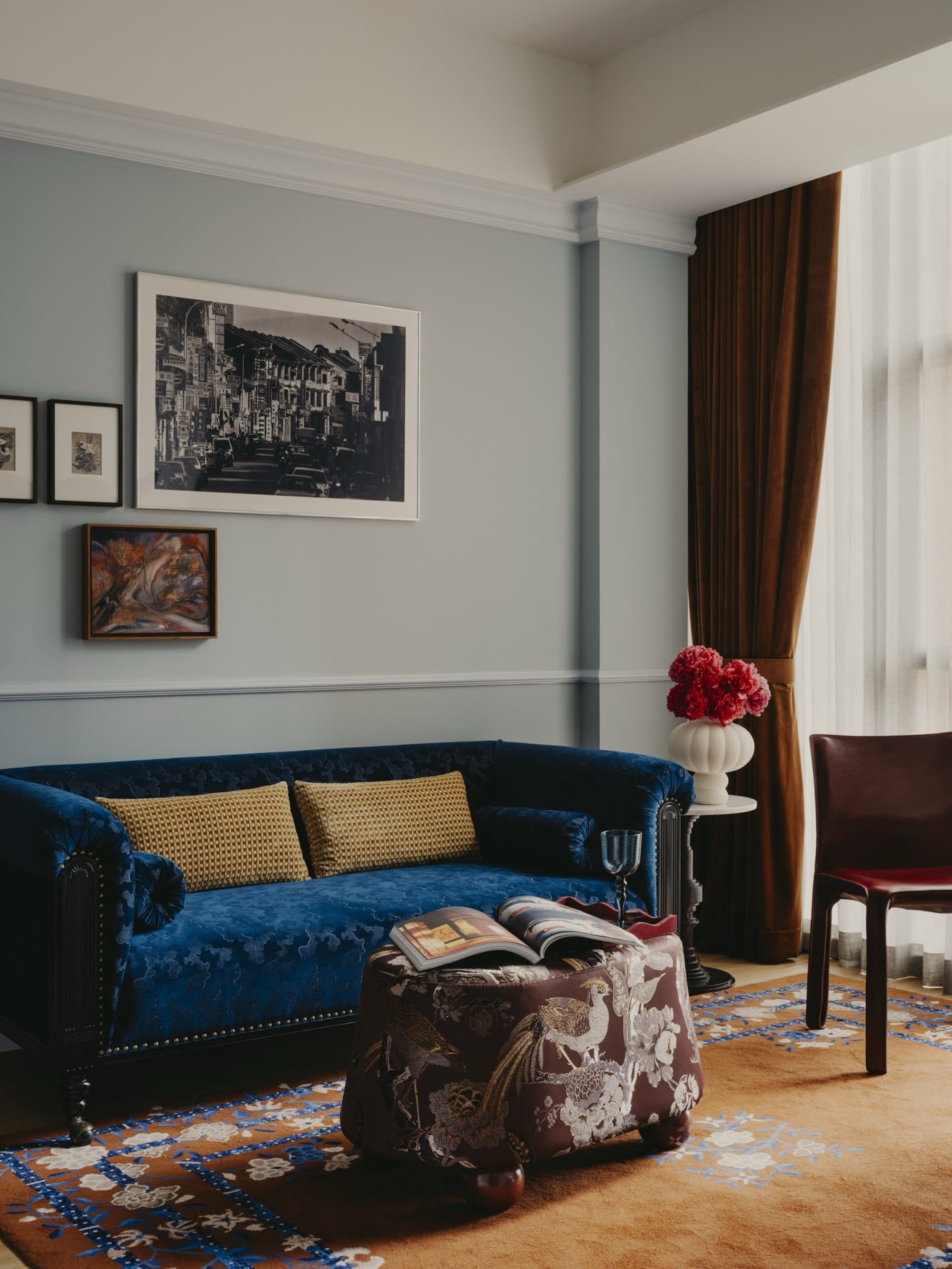 Zimmer im NoMad Singapore mit blauem Samtsofa, hellgruenen Waenden und gemustertem Teppich