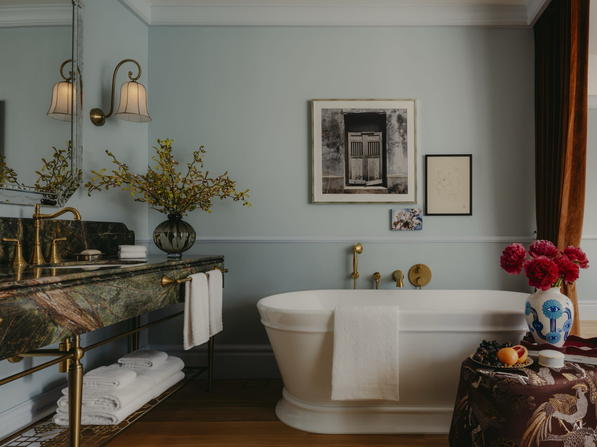 Badezimmer eines Zimmers im NoMad Singapore mit freistehender Badewanne und Waschbecken aus gruenem Marmor