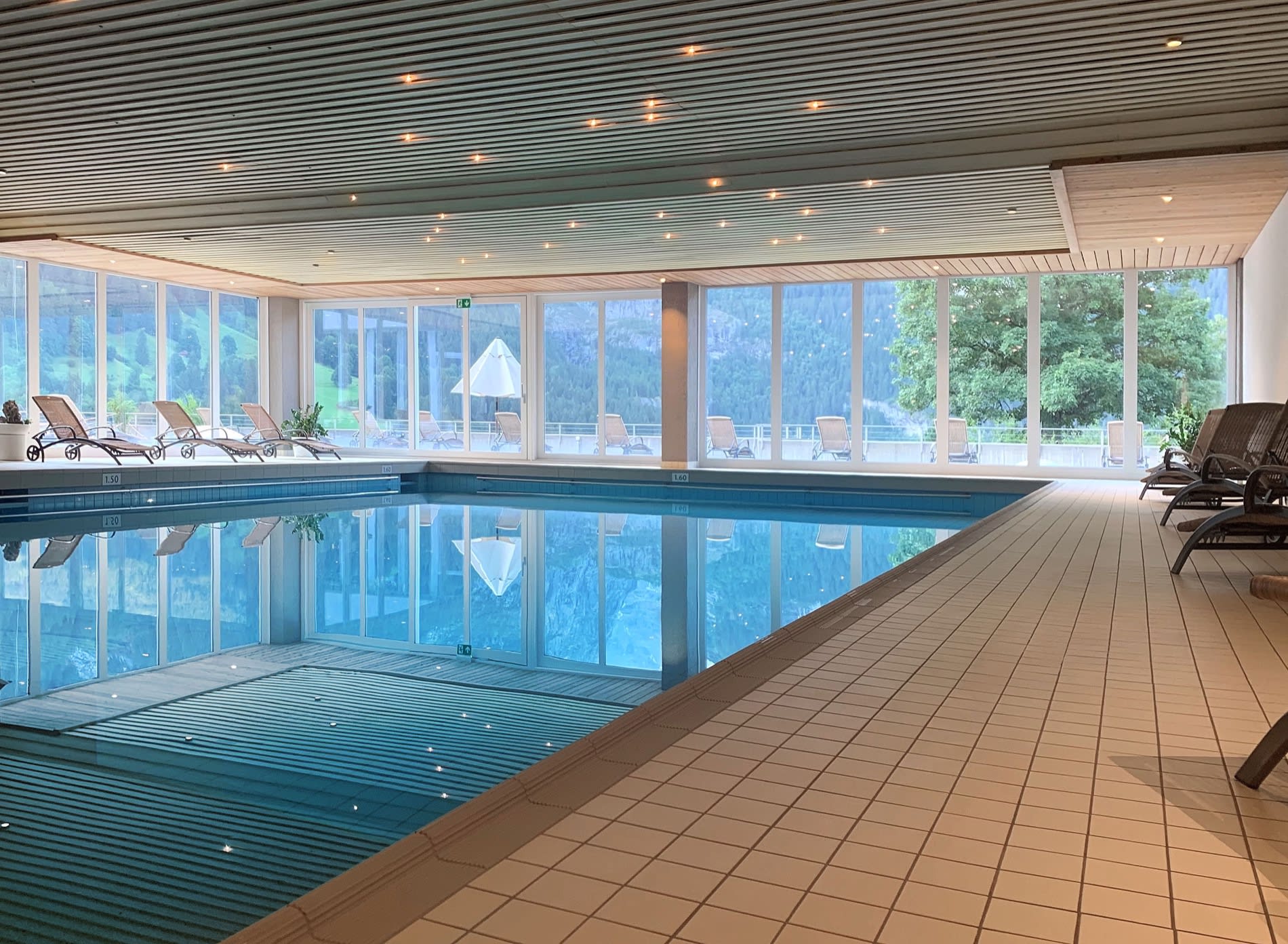 Bassin intérieur du spa du Sunstar Hotel Grindelwald, baies vitrées et plafond étoilé