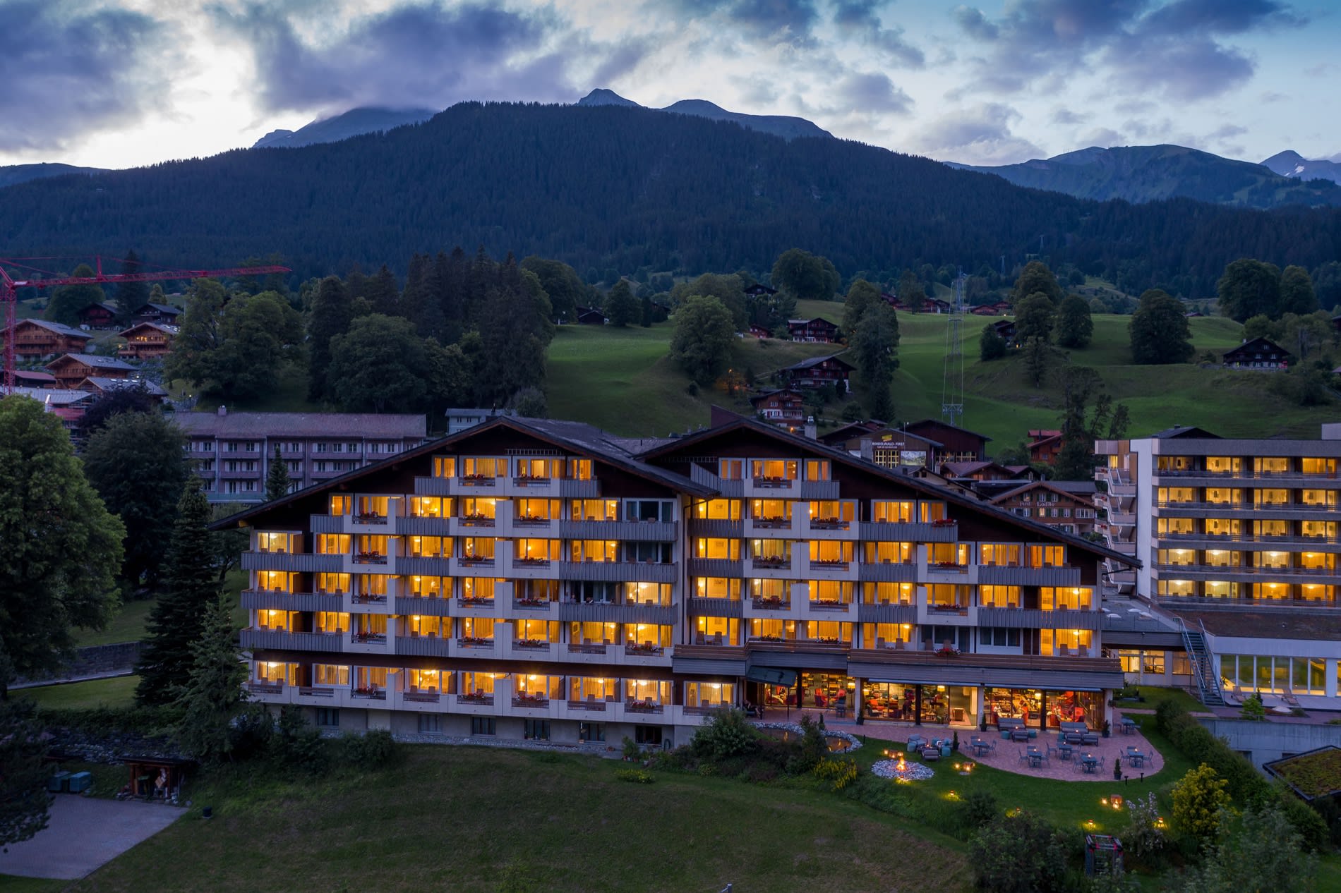 Vue aérienne du Sunstar Hotel Grindelwald illuminé au crépuscule, village et montagnes de l'Oberland bernois