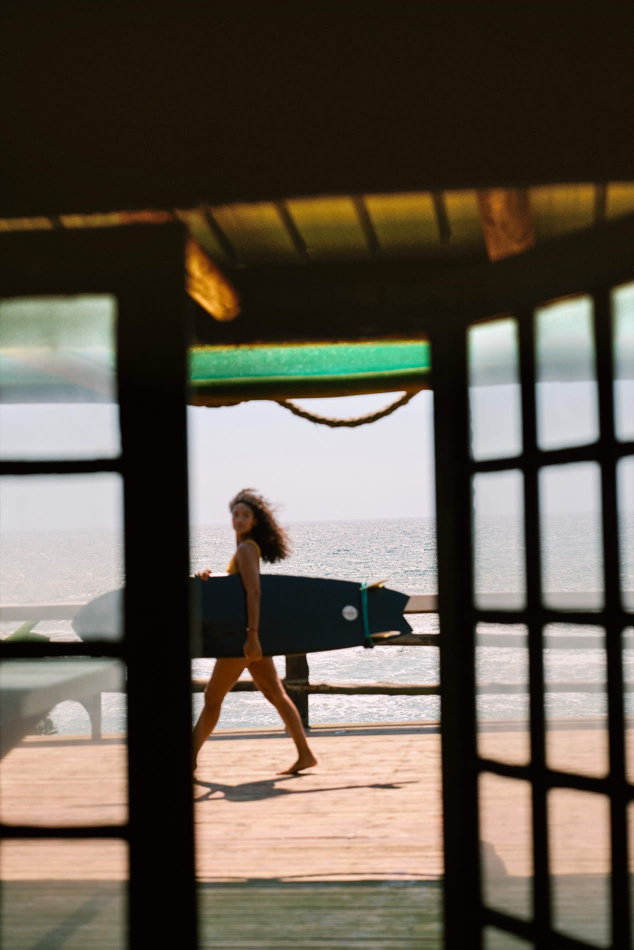 Surfer mit seinem Brett vor der Surfschule des Club Med South Africa Beach & Safari, Strand bei Sonnenuntergang
