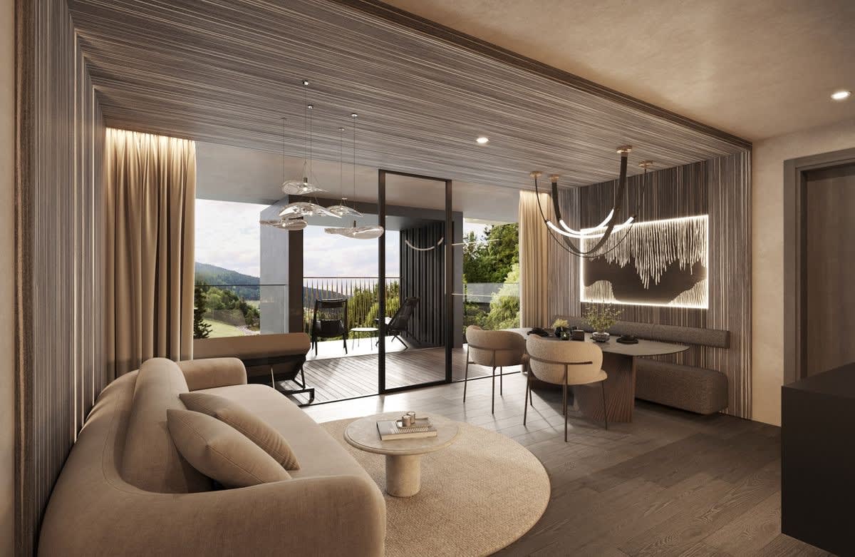 Living room of a Terra suite at the Viktoria Alpine Hideaway, rounded beige sofa, wood panelling and floor-to-ceiling window overlooking the valley