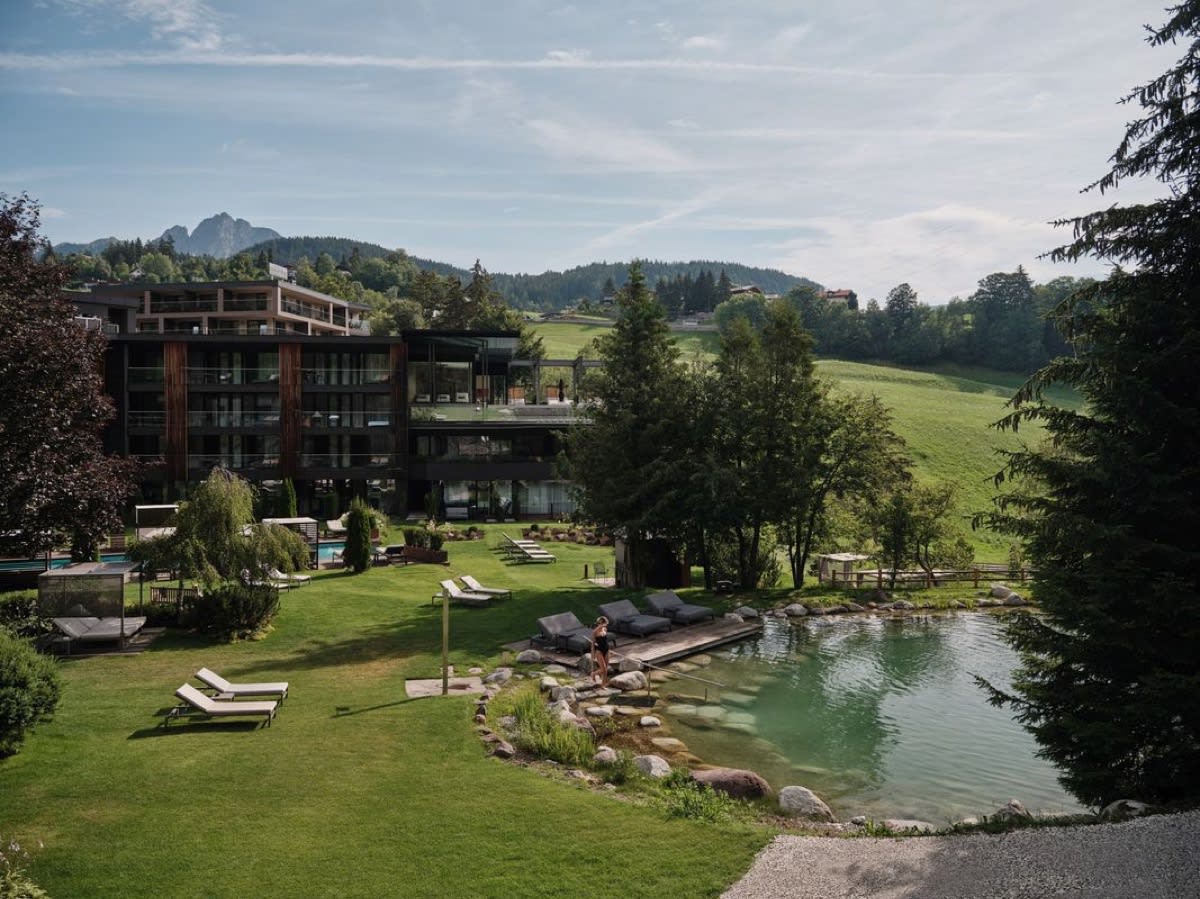 Natural pond and sun loungers in the garden of the Viktoria Alpine Hideaway, beneath the fir trees