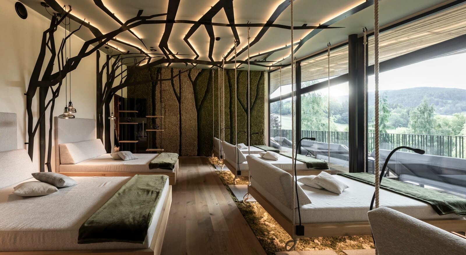 Terra suite at the Viktoria Alpine Hideaway, bed facing the floor-to-ceiling window, bathtub and hanging branches from the ceiling