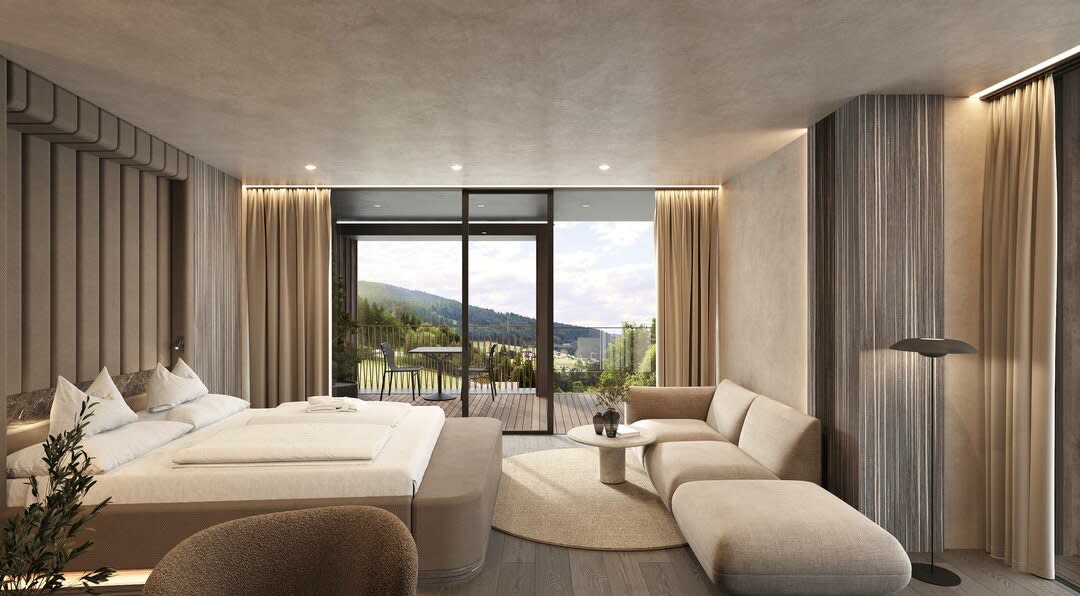 Bedroom of a Terra suite at the Viktoria Alpine Hideaway, white bed, armchairs and window overlooking the mountains