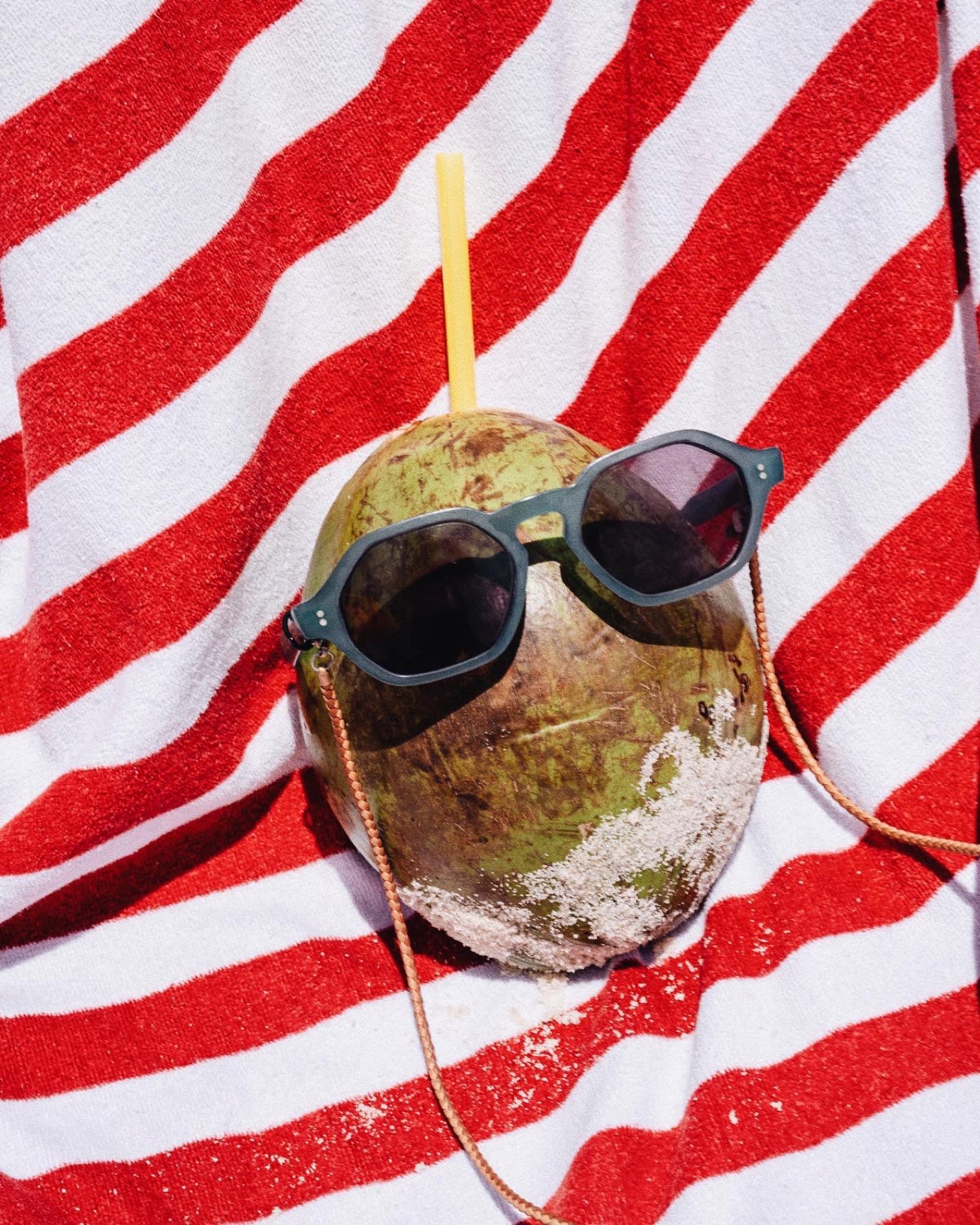 Coco fresco con gafas de sol sobre una toalla de rayas rojas y blancas junto a la piscina del Copacabana Palace