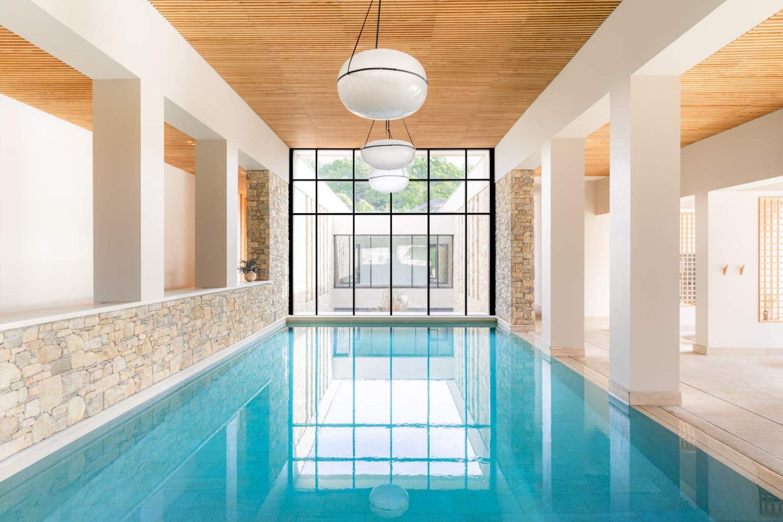 Indoor pool at the L'Occitane spa at Le Couvent des Minimes in Mane, featuring stone, light wood, and a glass roof