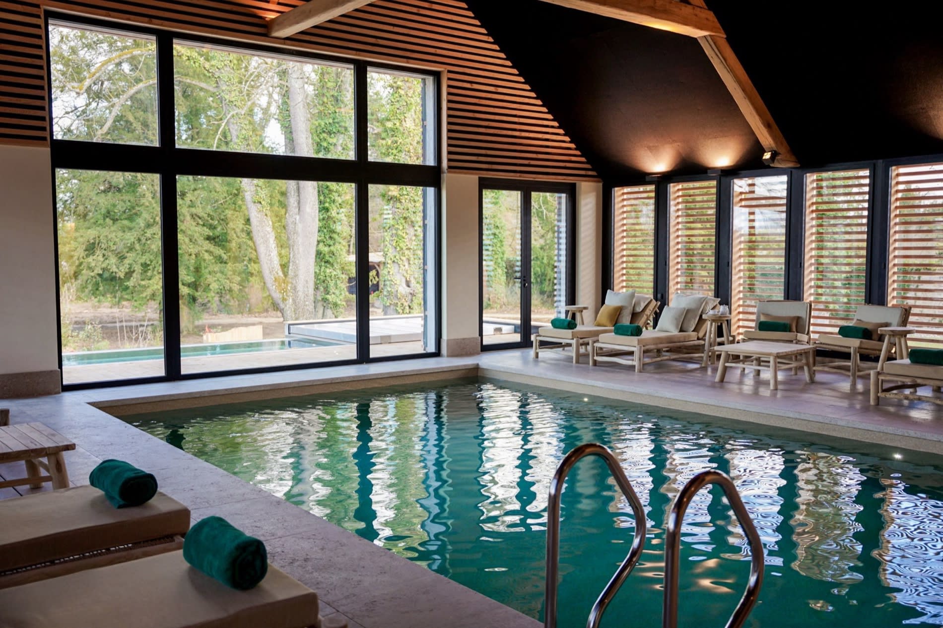 La piscine intérieure du Spa Sisley de l'Hostellerie de Levernois, ouverte par de grandes baies sur le parc, près de Beaune