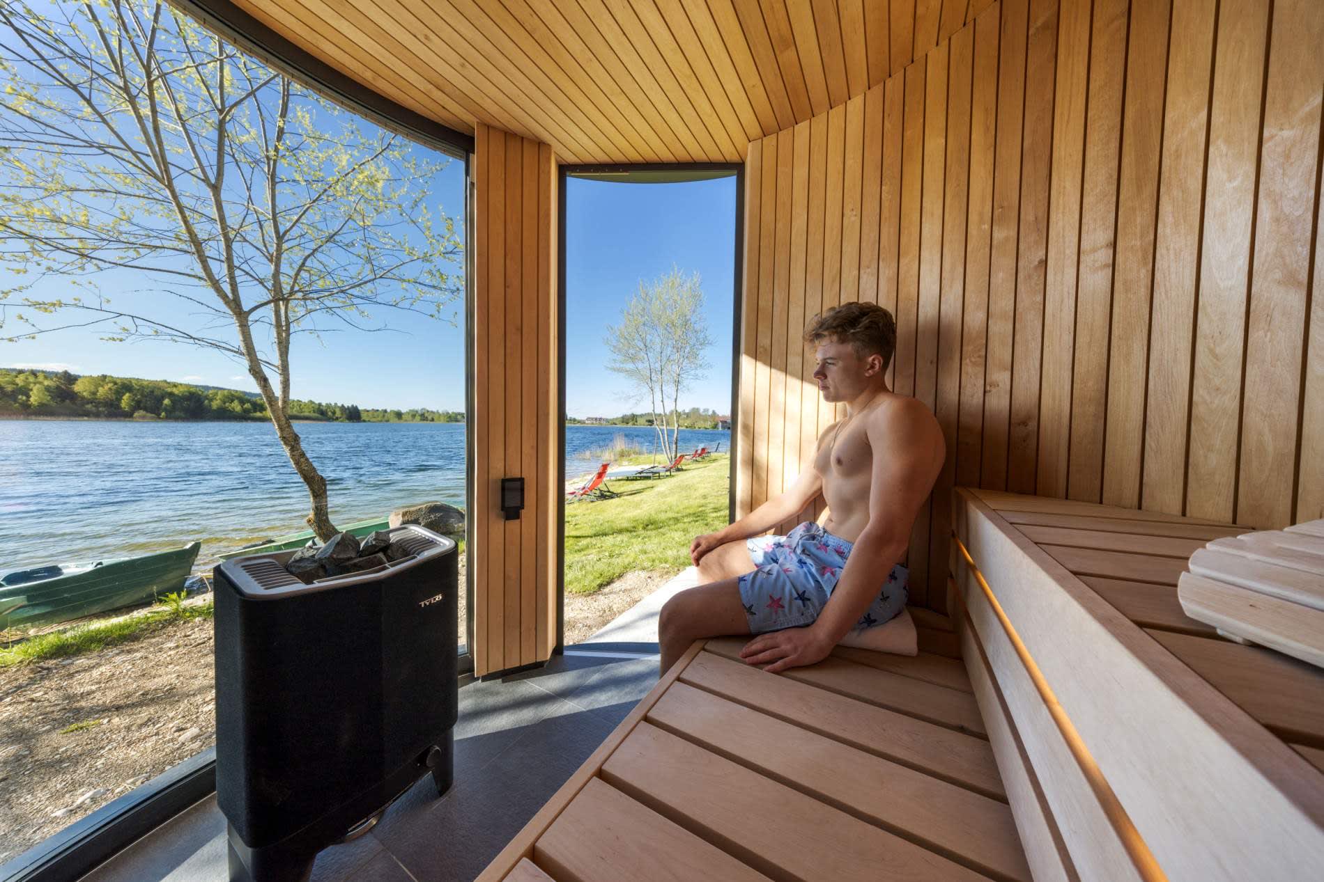 Le sauna extérieur en bois de l'Hôtel de l'Abbaye, ouvert par une baie vitrée sur le lac de l'Abbaye, à Grande-Rivière Château