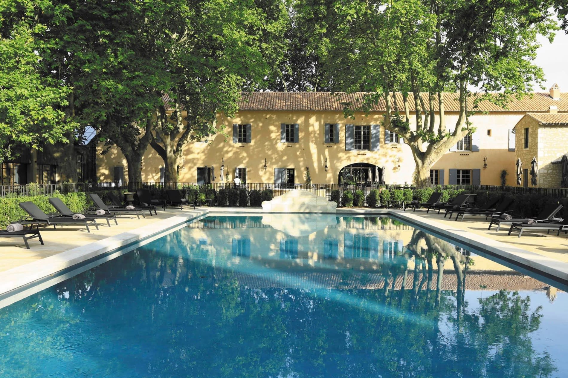 La piscine extérieure du Domaine de Manville devant le mas provençal et ses platanes, aux Baux-de-Provence
