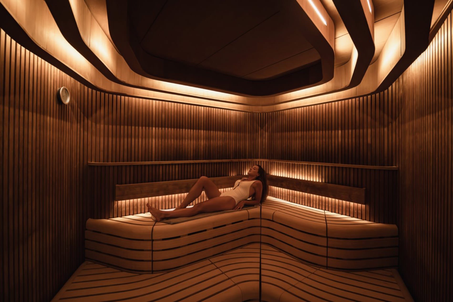 Le sauna en bois du spa des Haras Hôtel à Strasbourg, avec ses banquettes ondulées et son plafond sculpté rétroéclairé