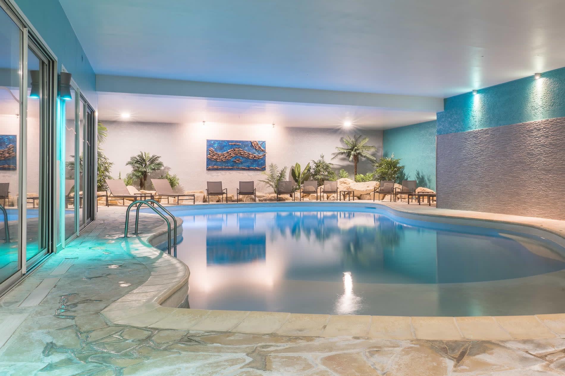 La piscine intérieure chauffée du Domaine de Villers et ses transats, derrière de larges baies vitrées, à Villers-sur-Mer