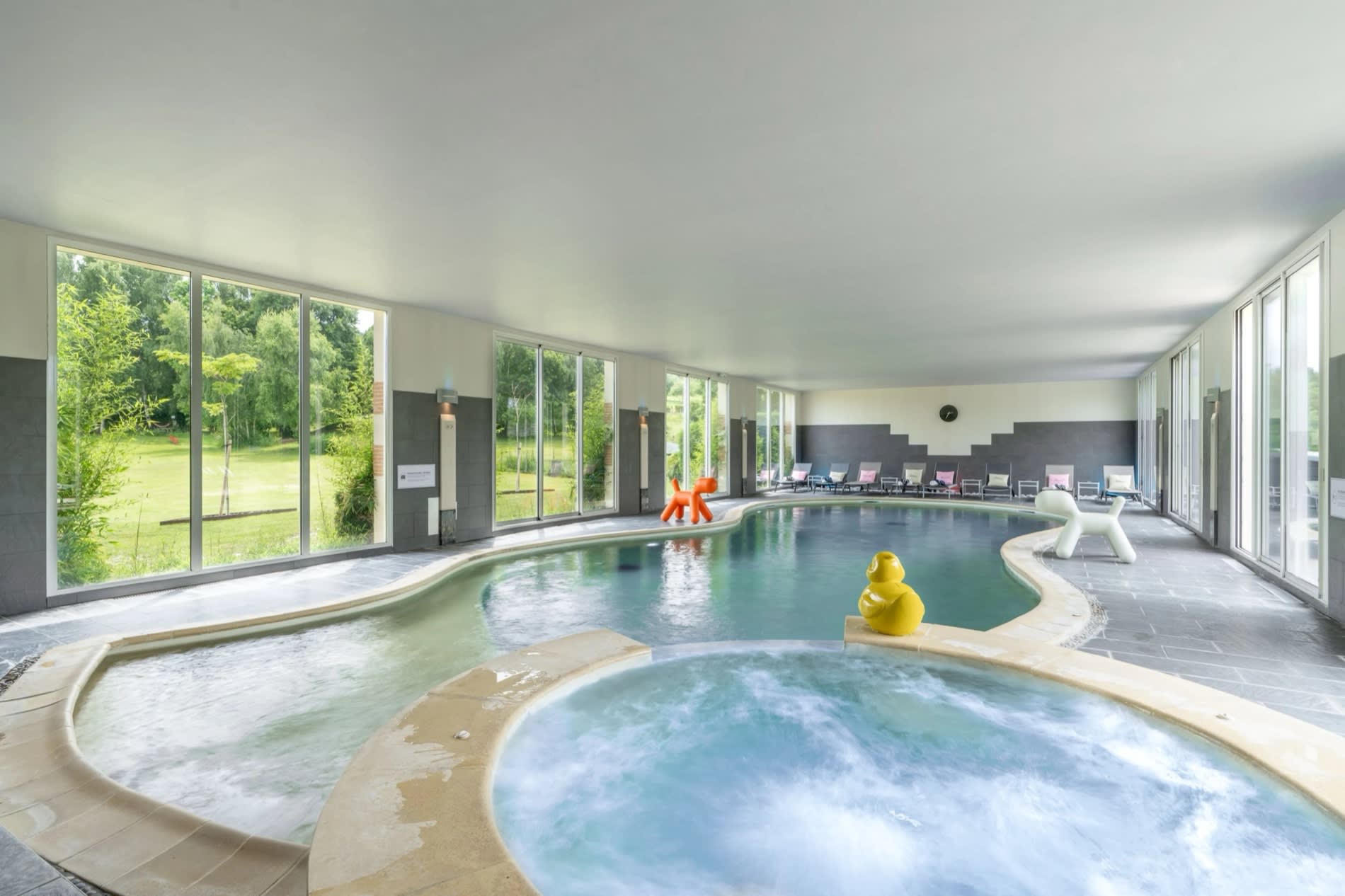 La piscine intérieure de 17 mètres du Manoir de la Poterie et son bain à remous, ouverte sur le parc, à Cricquebœuf