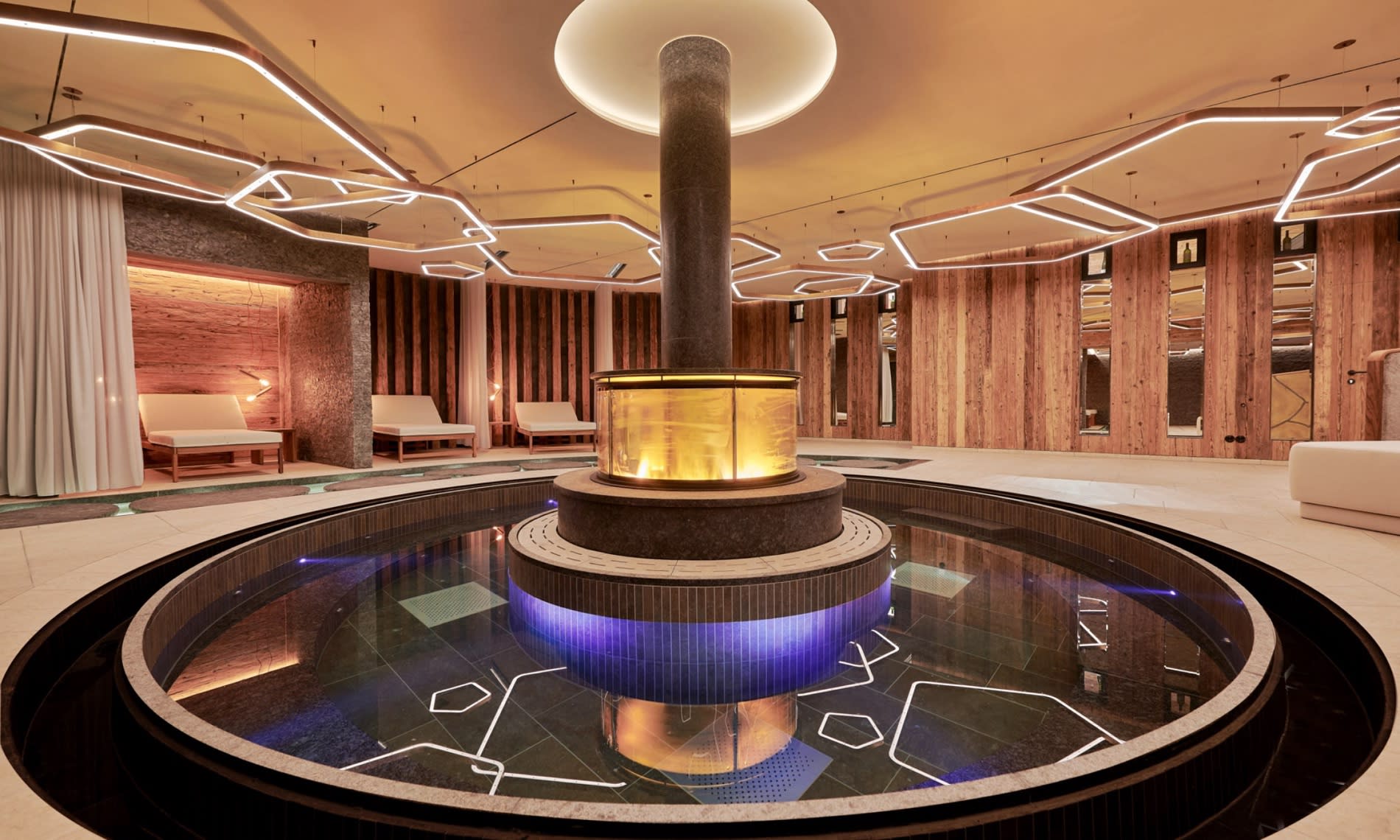El jacuzzi circular de la Burg Oase en el Burg Hotel Oberlech, hogar abierto de cobre en el centro, paredes de madera envejecida y tumbonas