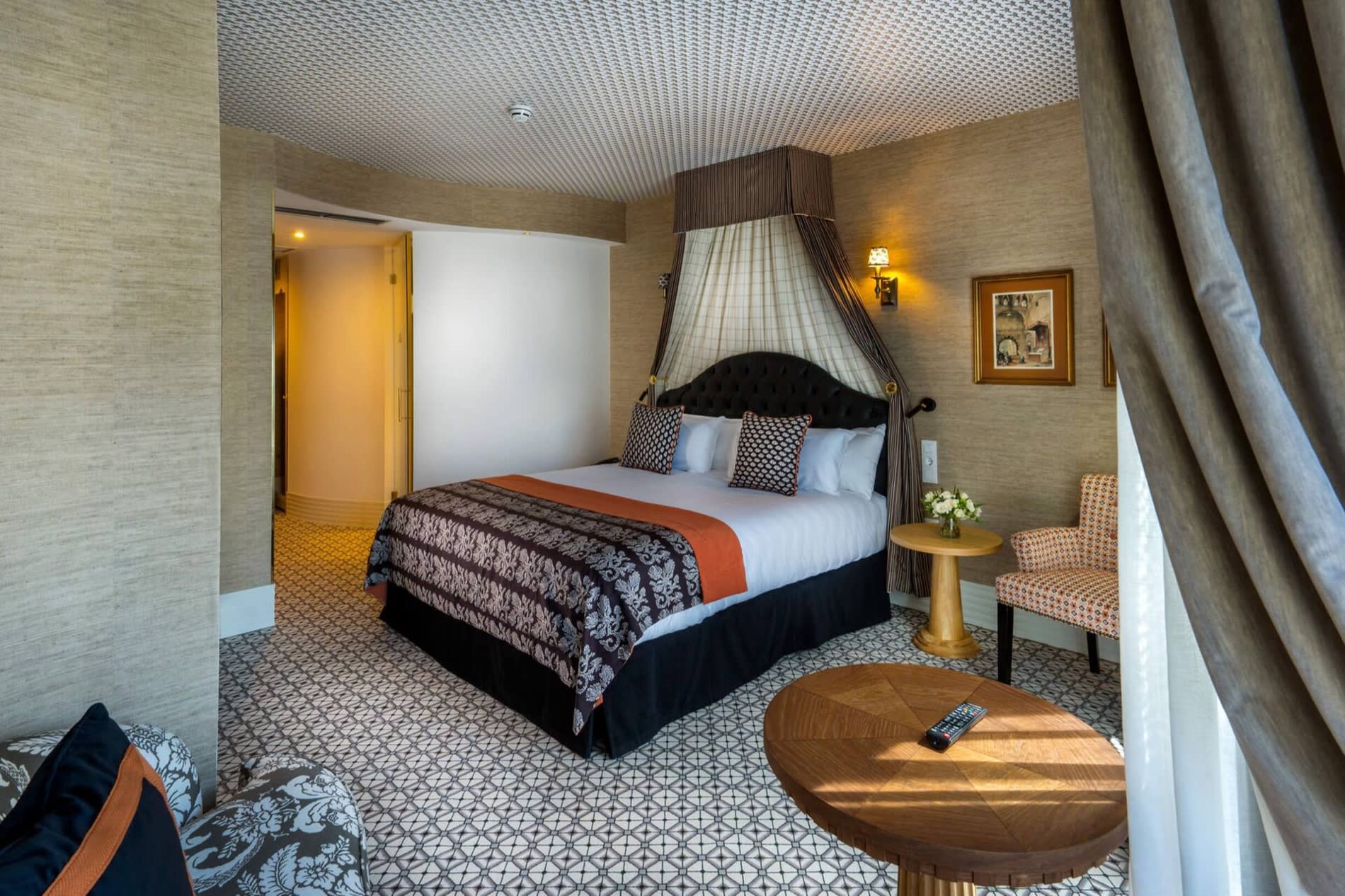 Junior Suite de Casa Verbena Madrid, ciel de lit en tissu raye, tete de lit capitonnee noire et moquette a motifs geometriques