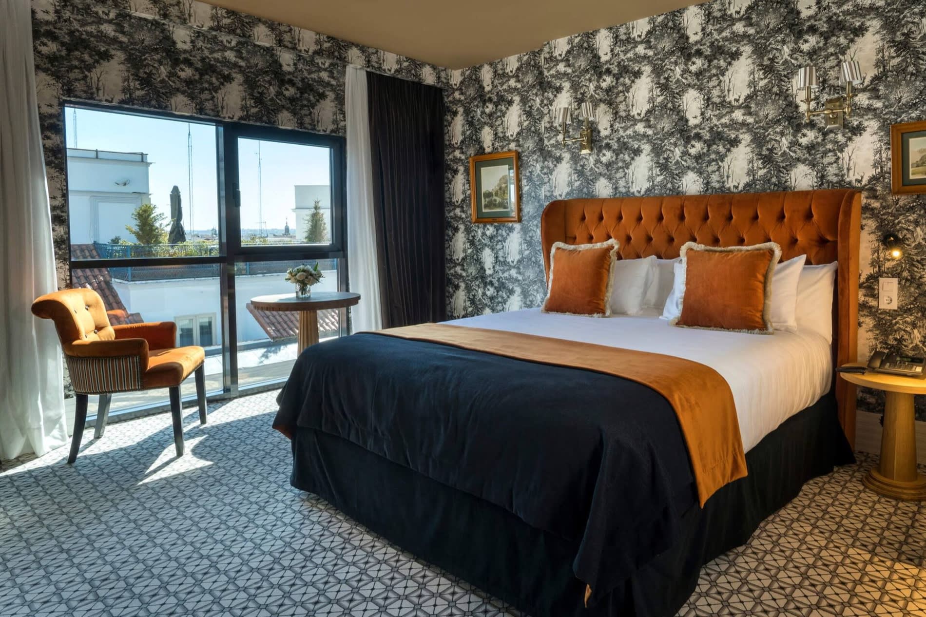 Chambre Premium de Casa Verbena Madrid, papier peint toile de Jouy, tete de lit en velours orange et porte-fenetre ouvrant sur une terrasse