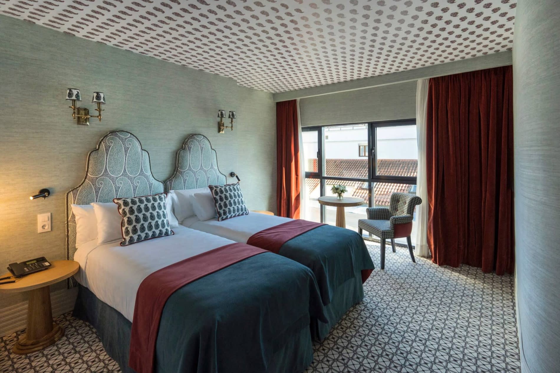 Chambre Superieure de Casa Verbena Madrid, lits jumeaux, tetes de lit cachemire et rideaux rouge brique devant les toits voisins