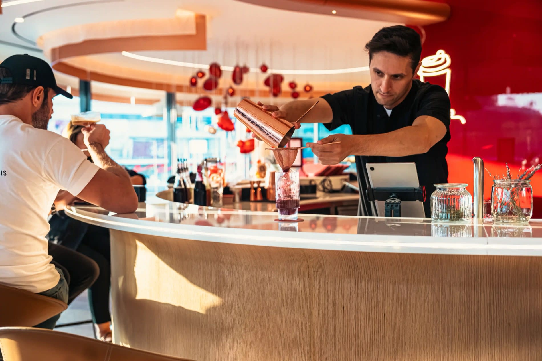 Barista de la Al Ameed Coffee Experience de Ammán sirviendo a un cliente en la barra curva