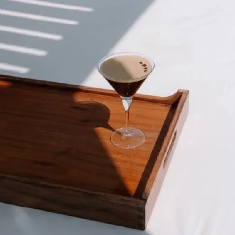 A signature cocktail served on a wooden tray at the La Pajarera rooftop of BLESS Barcelona