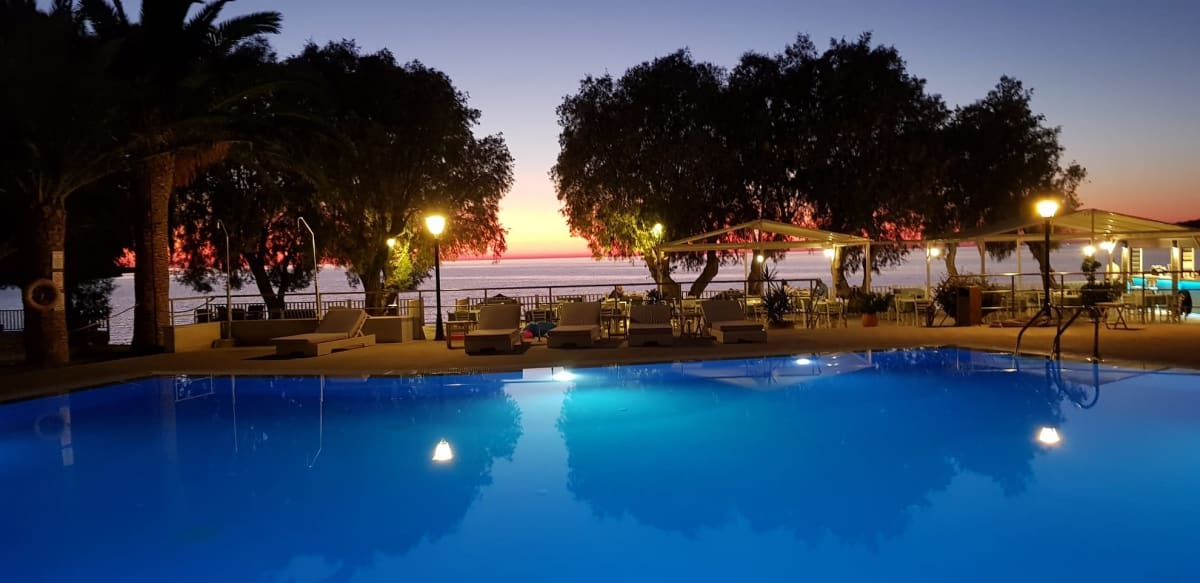 La piscina del hotel Aphrodite iluminada al anochecer, frente al mar Egeo