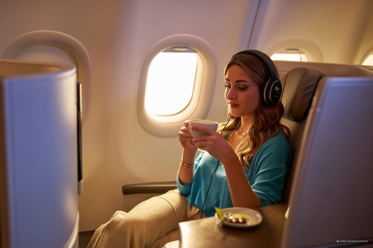 Banner promoting Airbnb Miles: large French headline over a glass-walled tropical dining room; man stands at a long table amid green accents on the sides.