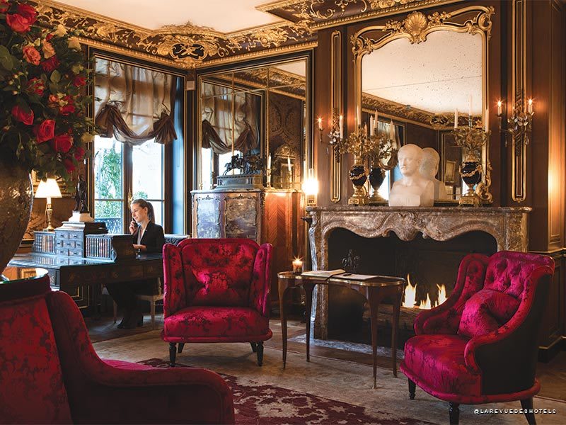 Le salon feutré de La Réserve Paris signé Jacques Garcia, velours rouge et cheminée d'époque