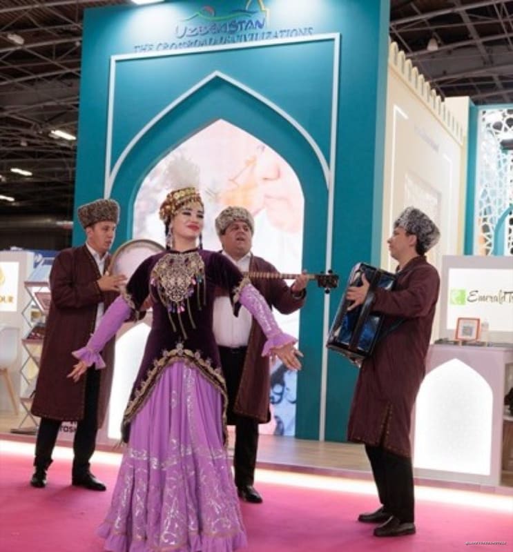 Busy exhibition hall with orange Selectour banners, pink carpet, and attendees visiting travel booths.