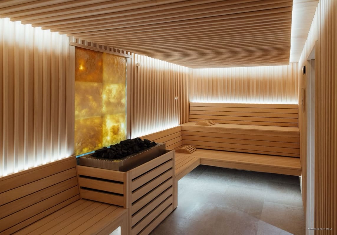 Sauna de madera clara con muro de sal retroiluminado en el Hôtel Barrière Le Normandy