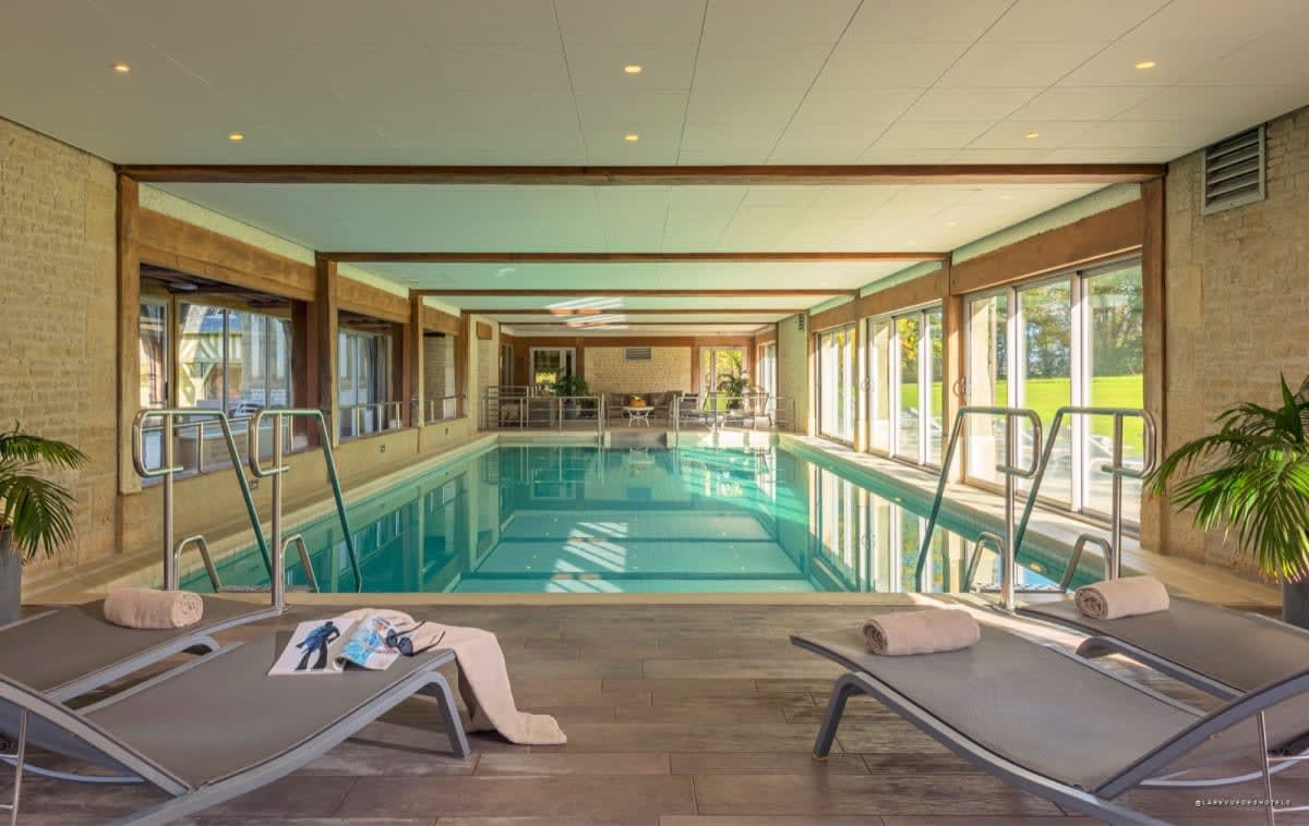 Piscina interior rodeada de tumbonas en Les Manoirs de Tourgéville