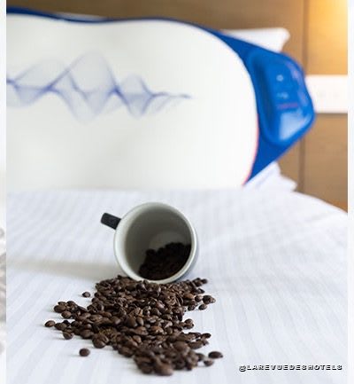 Des grains de café renversés sur un lit devant le Breakfast Pillow de Holiday Inn Express