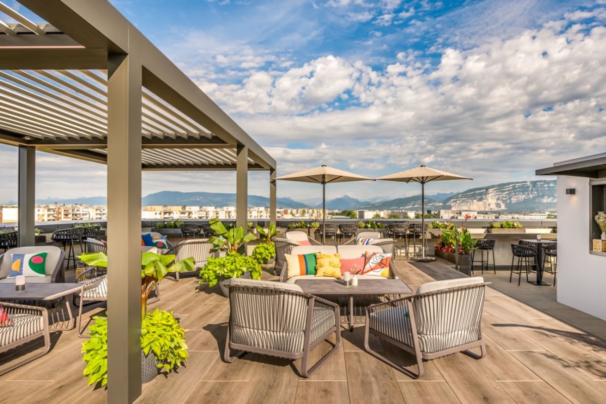 La terrasse du rooftop La Suite 1201, sous sa pergola, avec le Salève et le Jura à l’horizon