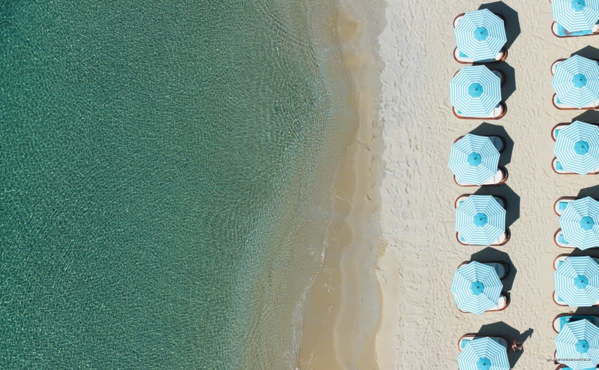 La plage du Nammos Resort AMAALA et ses parasols alignés sur la mer Rouge