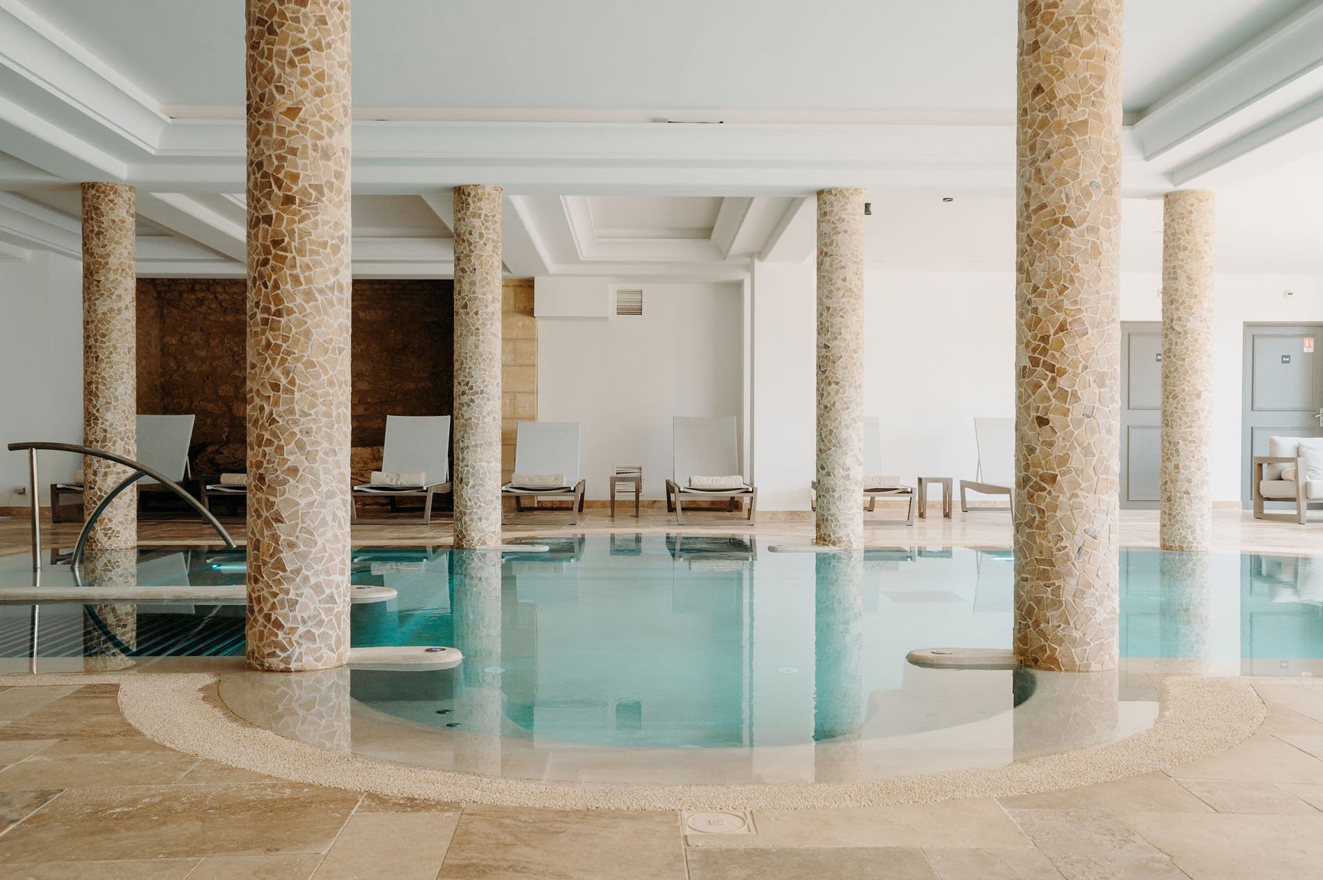 Le bassin du Spa Nuxe du Domaine de Rochebois entre colonnes de pierre