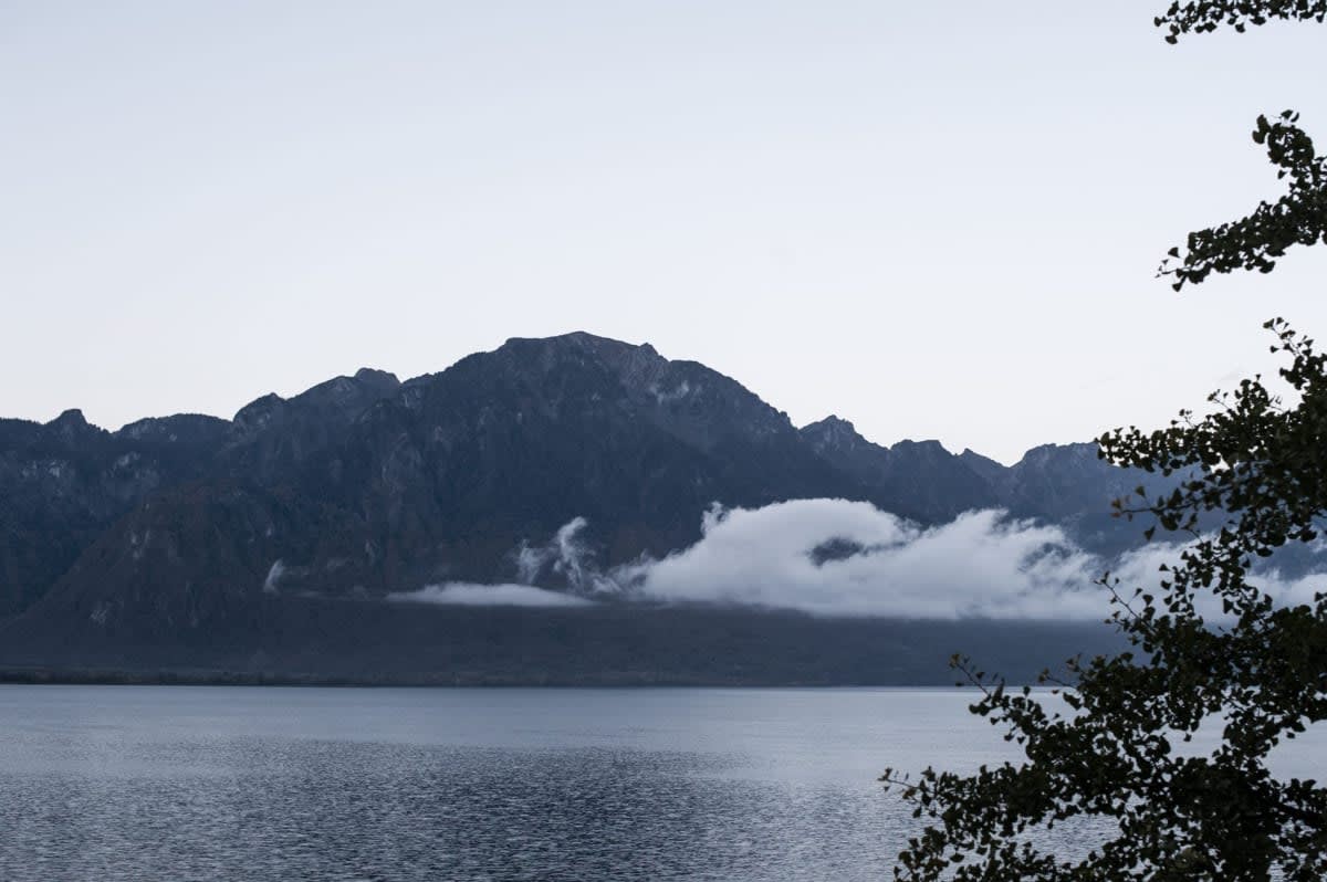 A mountain in the clouds above a calm lake