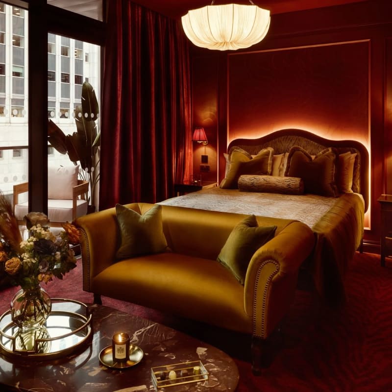Classic room at House of Gods Canary Wharf, velvet sofa, gilded bed and window overlooking the towers
