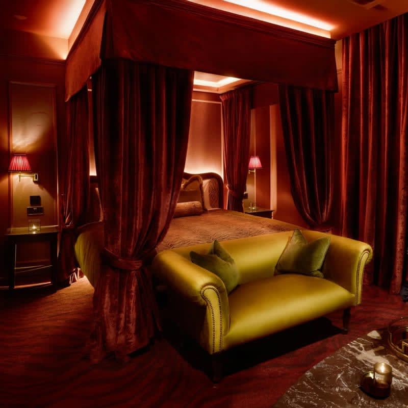 Suite at House of Gods Canary Wharf, red velvet four-poster bed and gilded sofa