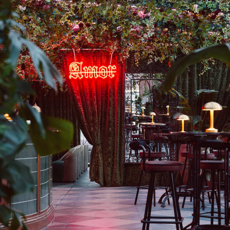 Rooftop of House of Gods in London, red Amor neon sign, greenery and high tables